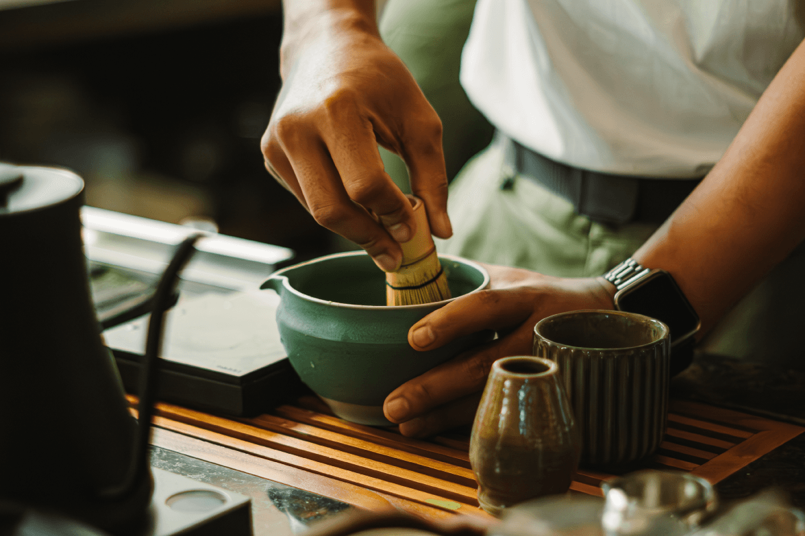 Matcha being whisked in a ceramic bowl at a café counter
