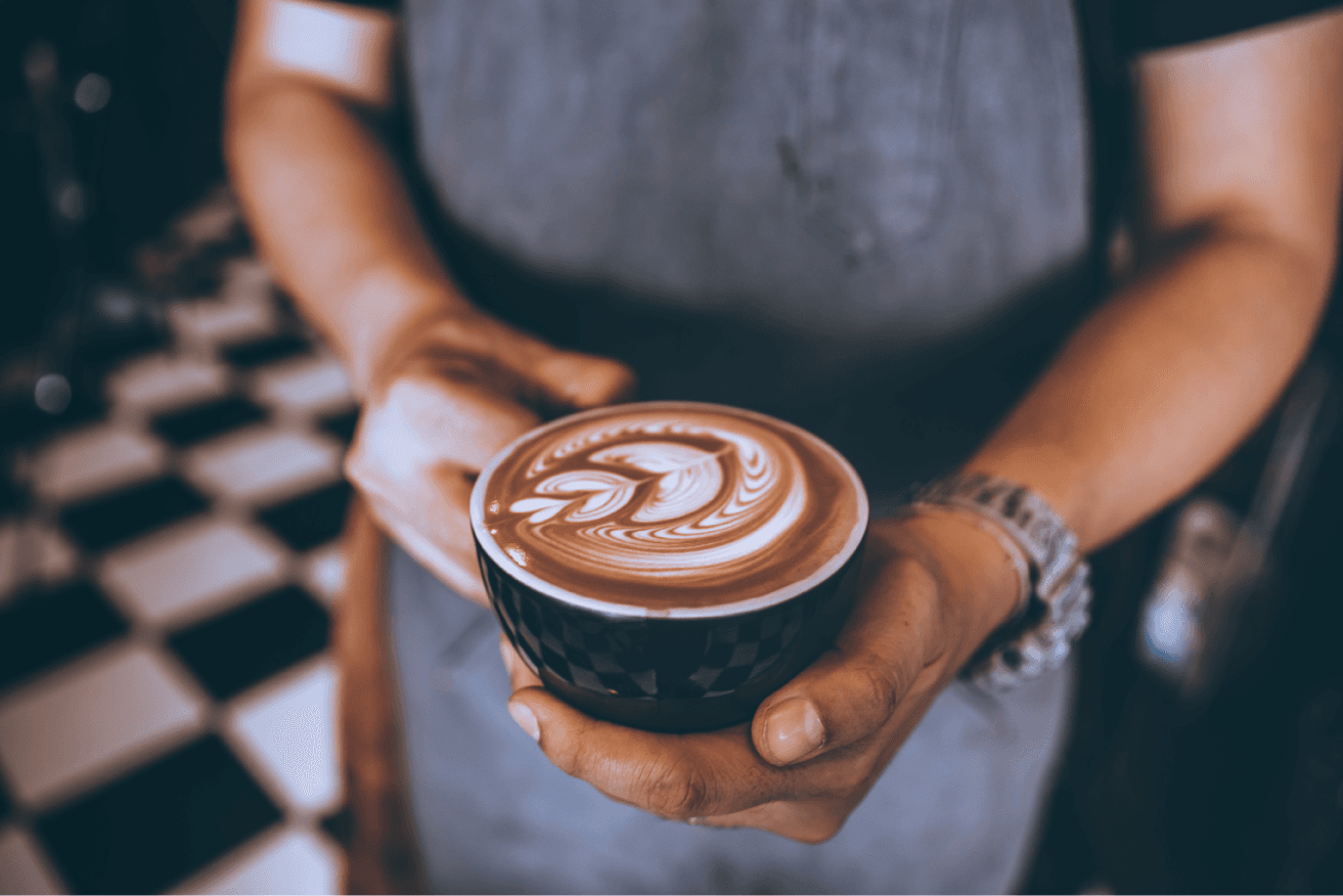 A barista holding a freshly prepared latte
